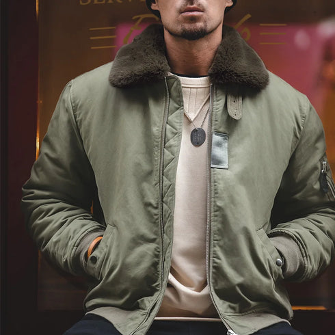 Man wearing a green jacket with a fur-lined collar in a dimly lit setting